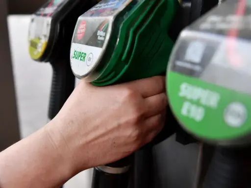 Hand greift nach Zapfhahn. Der steigende CO2-Preis macht sich beim Tanken bemerkbar.