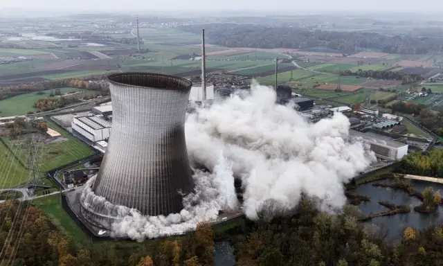 Ein Kühlturm stürzt ein, Staubwolken steigen auf. Ein Symbol für den **Atomausstieg Deutschland**.