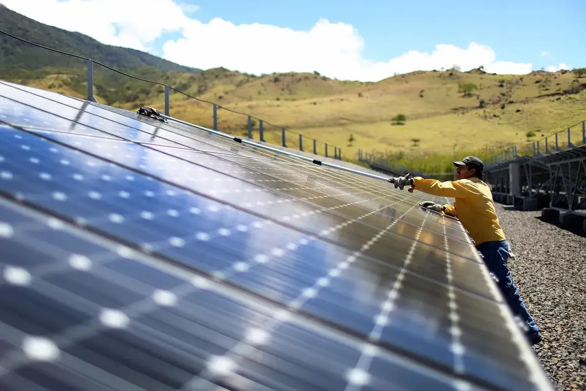 Mann reinigt Solarmodule in Costa Rica, ein Beispiel für erneuerbare Energien.