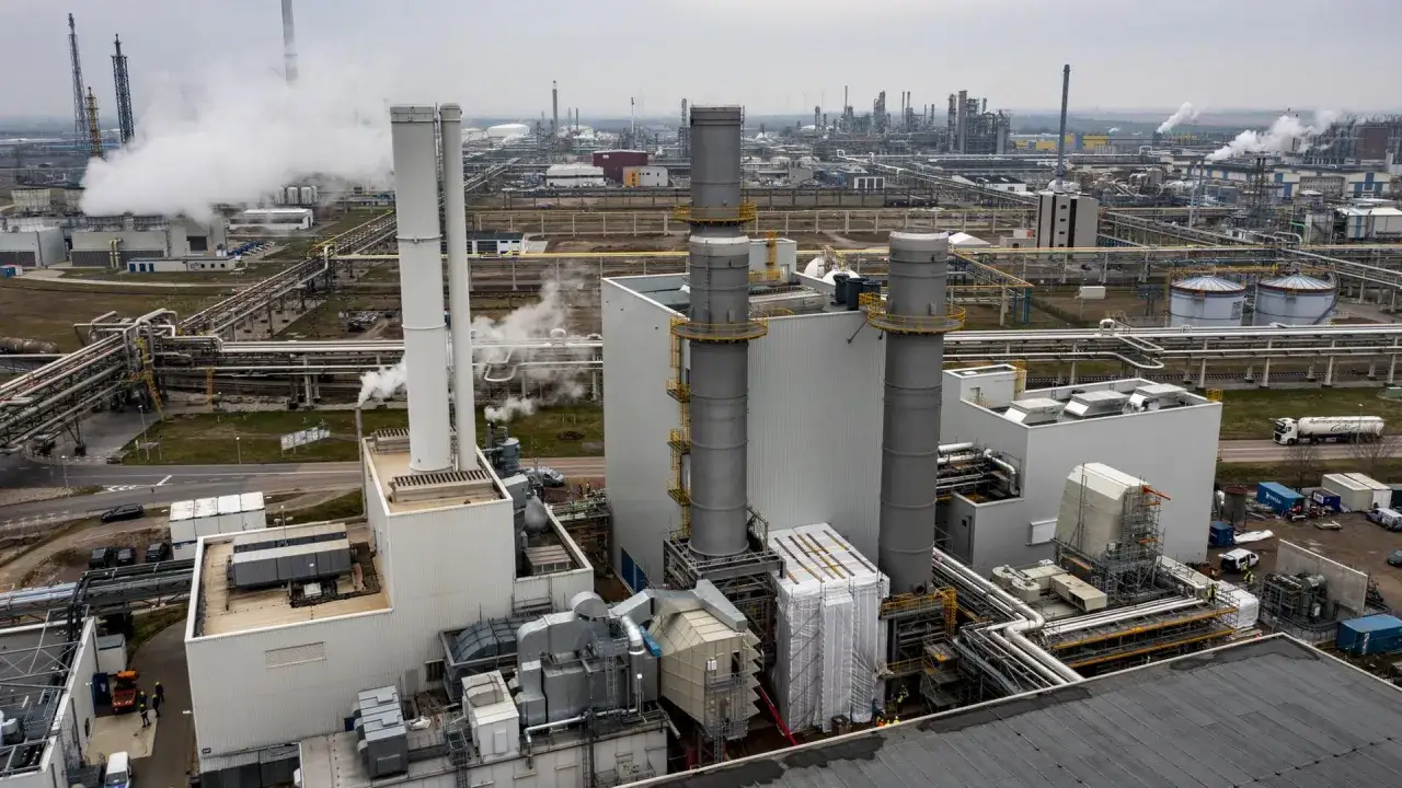 Industriekomplex mit Schornsteinen, Rohren und Gebäuden. Dampf steigt auf, ein Zeichen für die Gasverstromung in Deutschland.