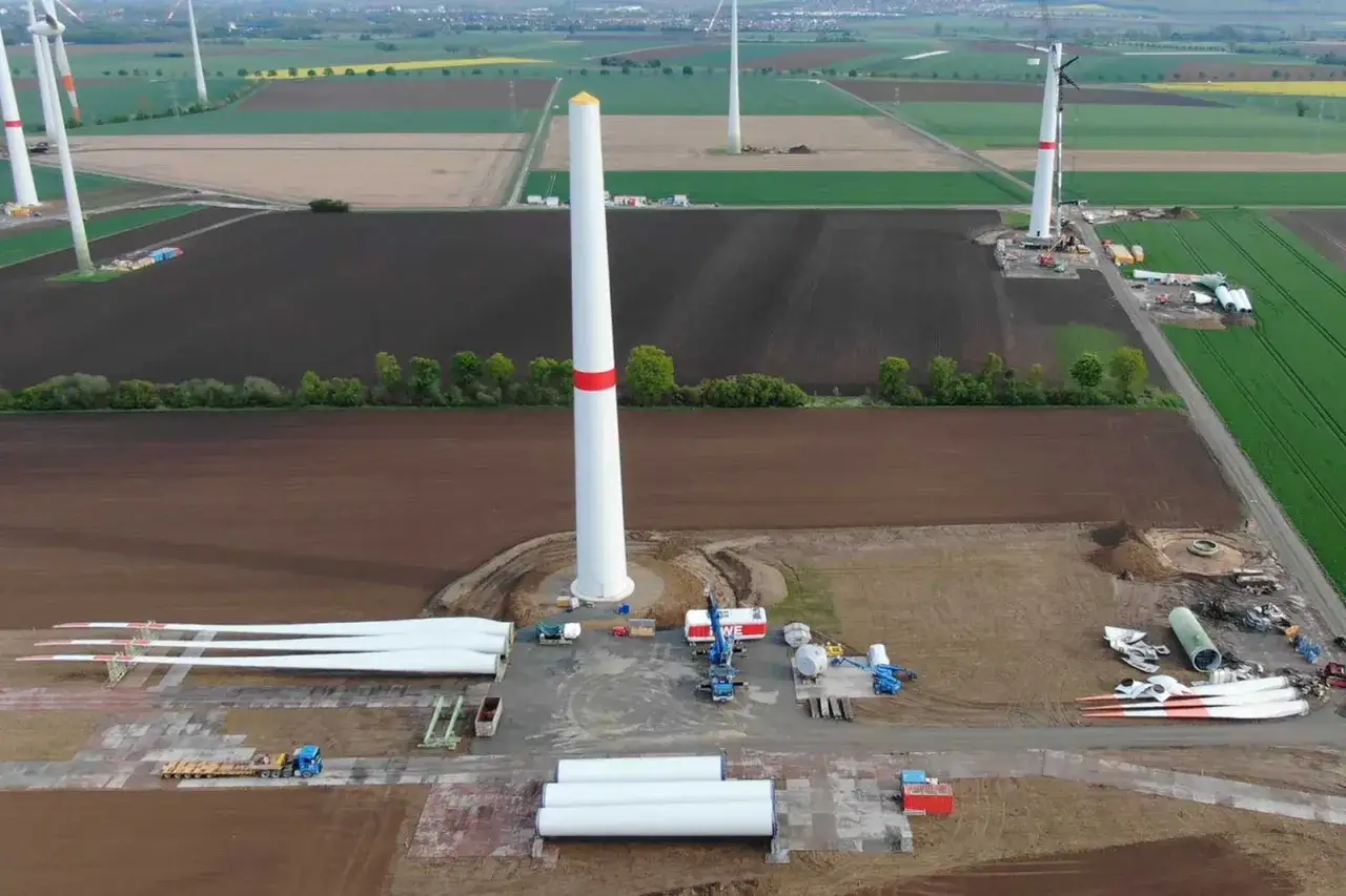 Baustelle für repowering von Windenergieanlagen. Neue Türme und Rotorblätter liegen bereit, während alte Anlagen demontiert werden.
