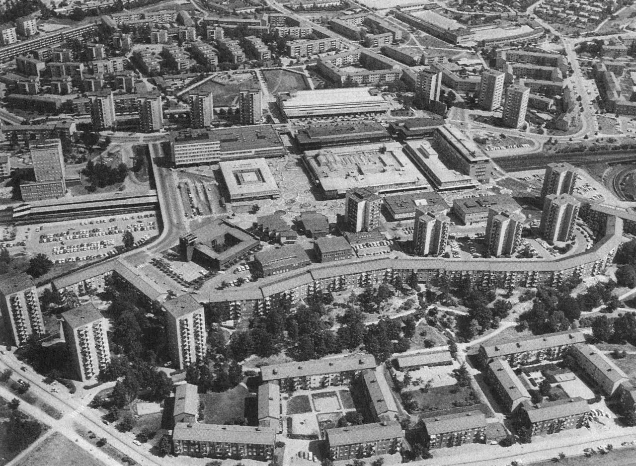 Luftaufnahme einer Stadt mit vielen Wohnblöcken und Hochhäusern, die das Ideal der autogerechten Stadt widerspiegeln.
