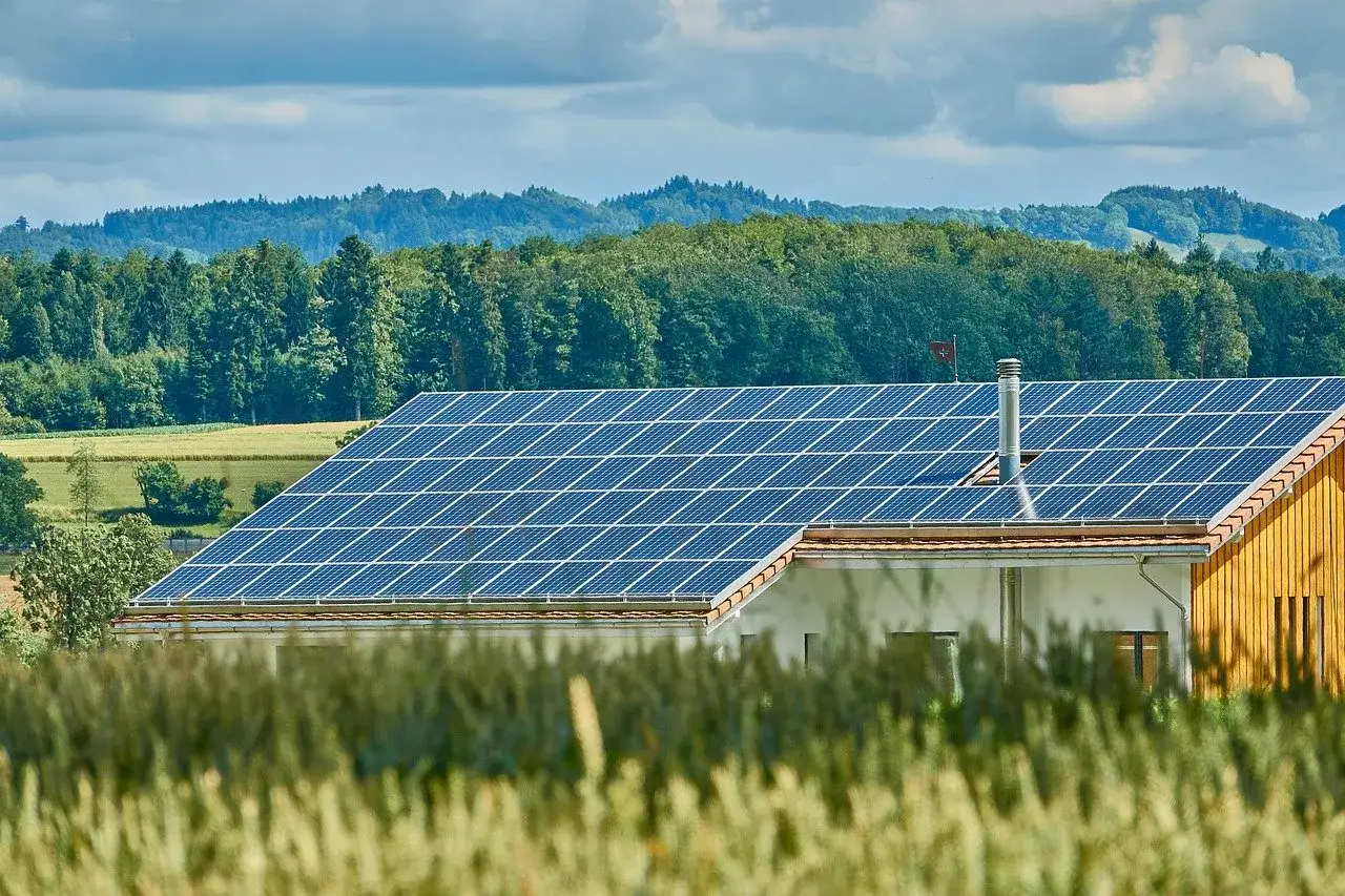Ein Haus mit Solaranlage auf dem Dach, ein Zeichen für Klimaschutz in Niedersachsen. Grüne Hügel im Hintergrund.