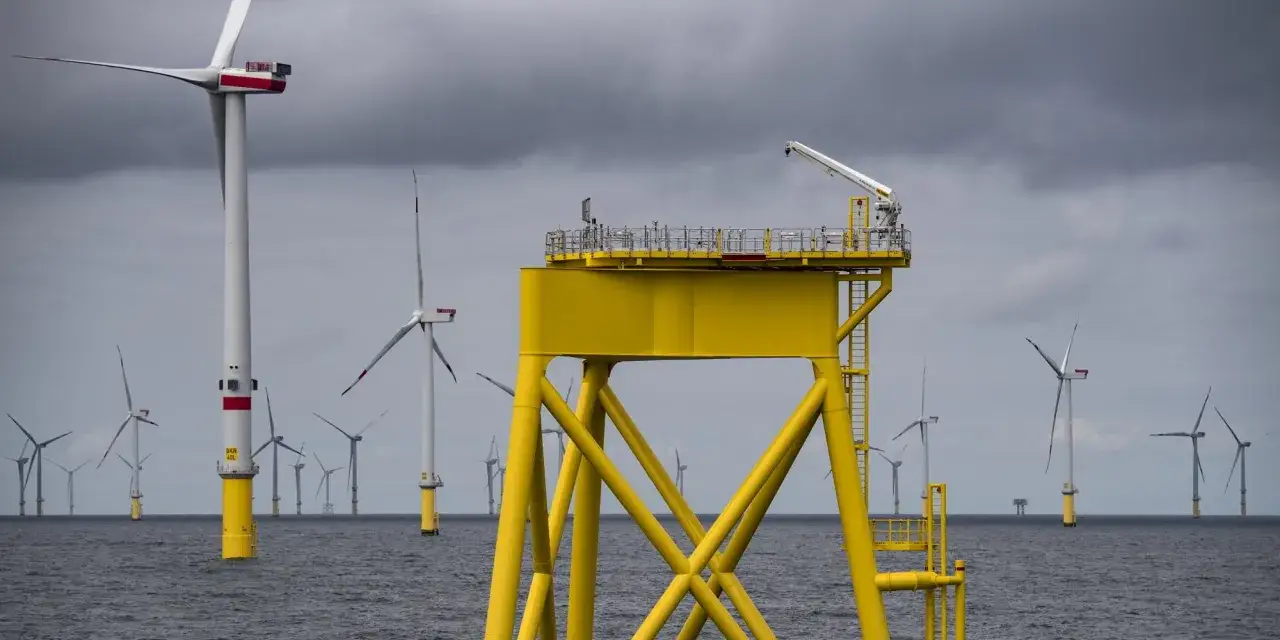 Windkraft-Energie: Mehrere Windräder im Meer, im Vordergrund eine gelbe Plattform mit Kran.