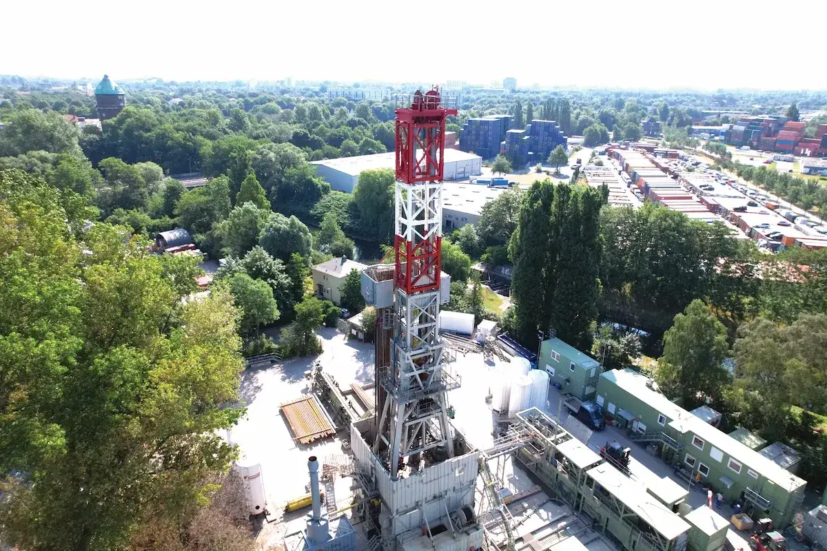 Bohrplattform für tiefe Geothermie, umgeben von Bäumen und Industriegebäuden.