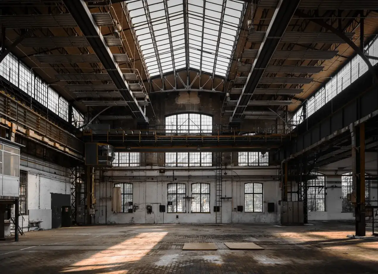 Große, leere Industriehalle mit Oberlichtern und Kranbahn. Ein Symbol für den regionalen Strukturwandel und die Transformation von Industrielandschaften.