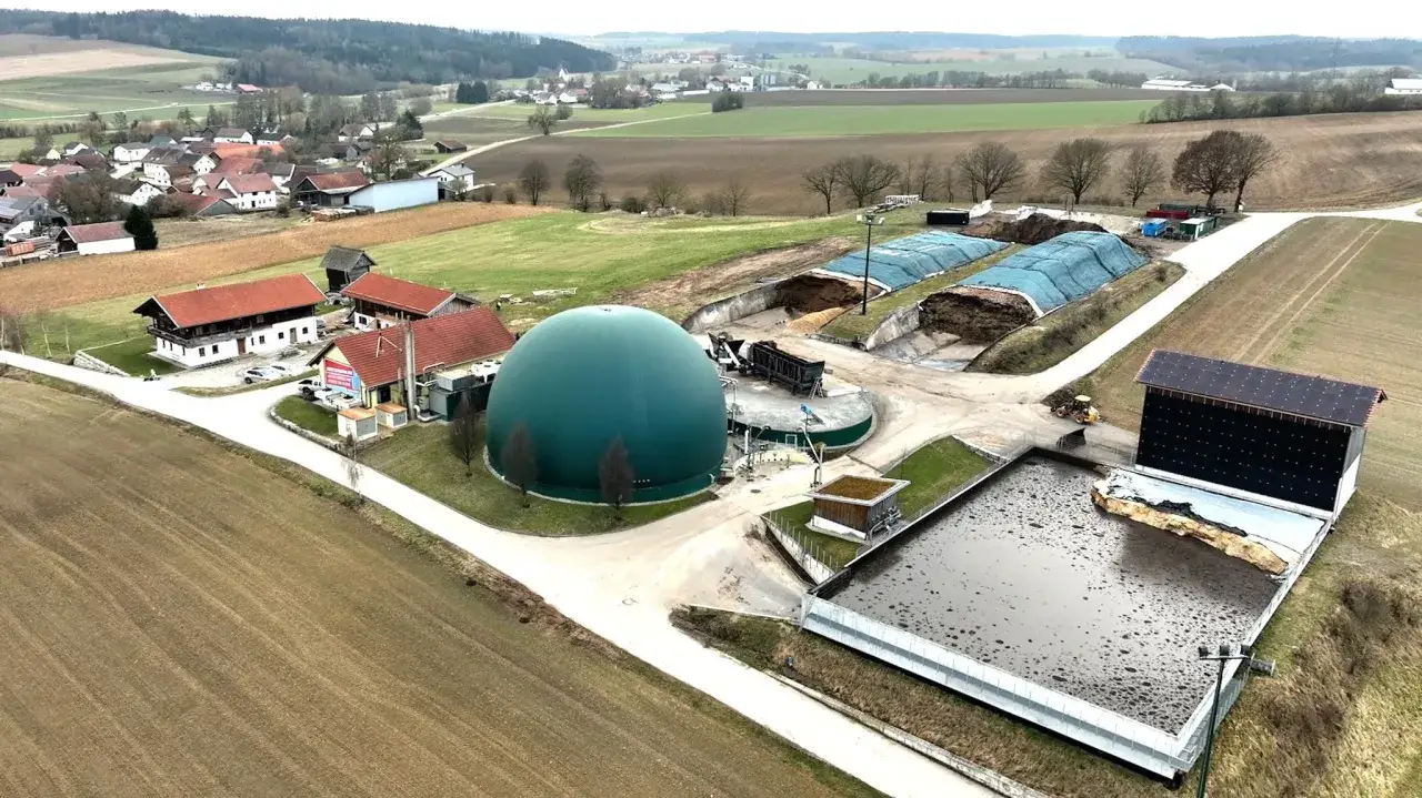 Grüner Gasspeicher-Ballon auf einer Biogasanlage, umgeben von Silagehaufen, einem Güllebecken und landwirtschaftlichen Gebäuden.