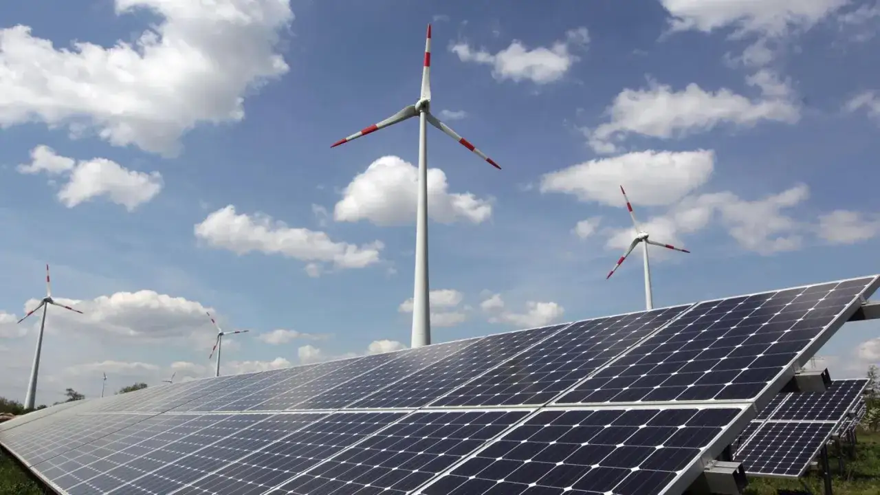 Windräder und Solarpanels unter blauem Himmel. Welche erneuerbare Energie ist die beste? Hier sehen wir zwei wichtige Technologien im Einsatz.