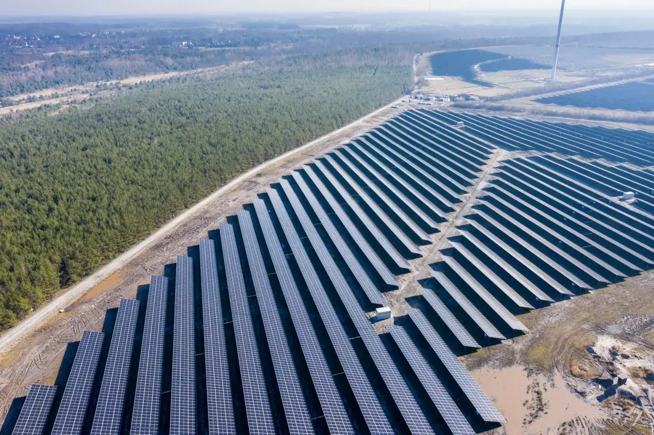 Große Solaranlage im Energiepark Lausitz, umgeben von Wald und Feldern.