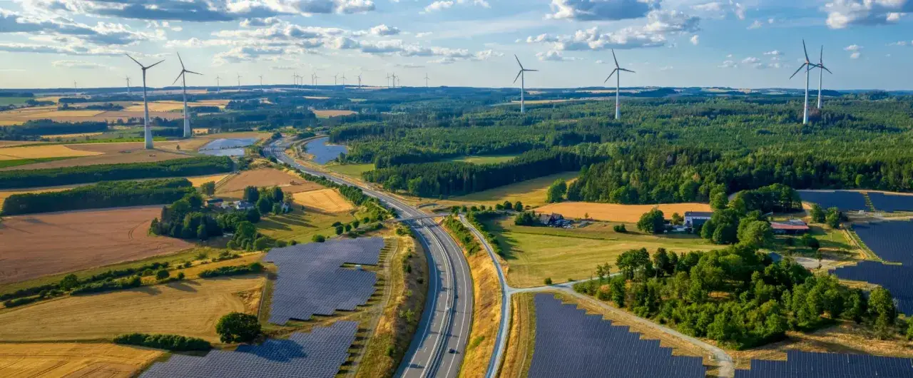 Weite Landschaft mit Windrädern und Solarparks, die die Entwicklung erneuerbarer Energien in Deutschland symbolisieren.
