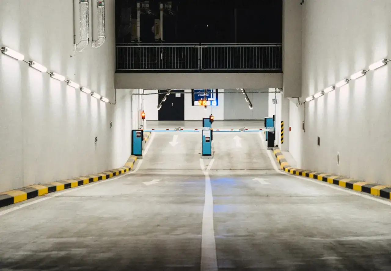 Einfahrt in eine Tiefgarage mit Schranken und Pfeilen, die den Weg weisen. Effizientes Parkraum Management für reibungslosen Verkehrsfluss.