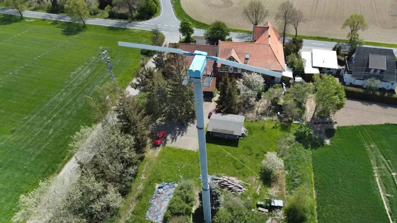 Eine kleinwindkraftanlage steht neben einem Einfamilienhaus mit roten Ziegeln.