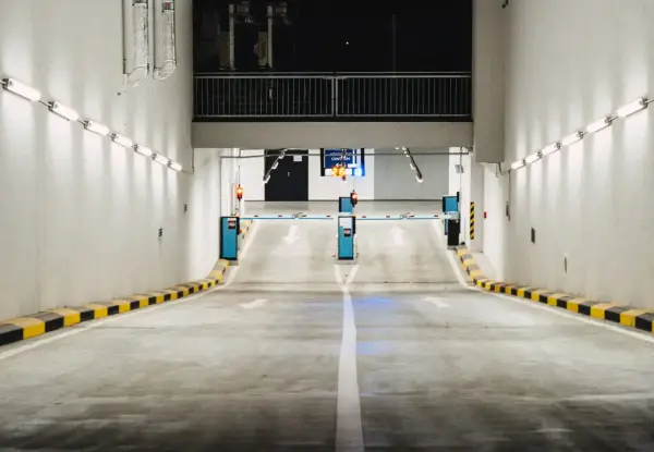 Einfahrt in eine Tiefgarage mit Schranken und Pfeilen, die den Weg weisen. Effizientes Parkraummanagement sorgt für Ordnung.