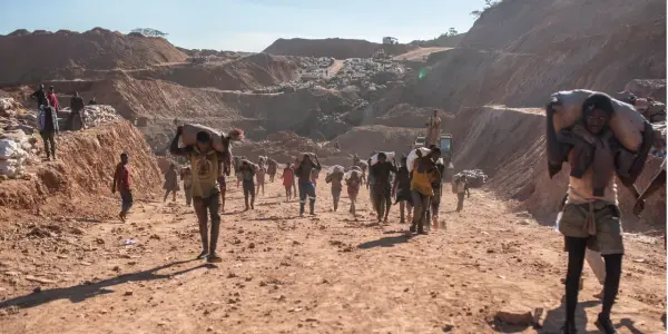 Kinder tragen schwere Säcke im Lithium-Abbau. Die harte Arbeit im Steinbruch zeigt die Realität von Kinderarbeit.